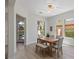 Bright dining room with wood table, bench, chairs, modern lighting, and backyard views from the windows at 17 Winding Rd, Henderson, NV 89052