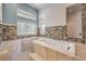 Modern bathroom with soaking tub surrounded by unique tiled walls and window at 2017 Slow Wind St, Las Vegas, NV 89134