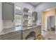 Well-lit laundry room with tile countertop, stainless sink, and custom storage cabinets at 2017 Slow Wind St, Las Vegas, NV 89134