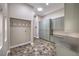 Laundry room featuring a circular skylight, custom cabinets, stainless countertops, and stone floors at 2017 Slow Wind St, Las Vegas, NV 89134