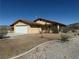Single-story home with tan stucco, tile roof, an attached garage, and a xeriscaped yard for low maintenance at 3090 N Woodchips Rd, Pahrump, NV 89060