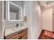 Modern bathroom vanity with a lighted mirror, wood-look cabinet, and hardwood floors at 6 Montana Way, Henderson, NV 89015