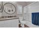 Well-lit bathroom with a round mirror, neutral-toned countertops, a shower with glass doors, and modern fixtures at 6245 Galileo Dr, Las Vegas, NV 89149