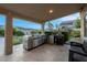 Covered outdoor kitchen featuring a built-in BBQ, mini fridge, and pizza oven with desert views at 6245 Galileo Dr, Las Vegas, NV 89149