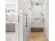 Elegant walk-in shower with white marble tiles, a wooden bench, and dual shower heads at 671 Scenic Rim Dr, Henderson, NV 89012