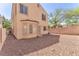 View of the back of the two-story home featuring rock landscaping, privacy walls and mature trees at 7621 Breed Hill St, Las Vegas, NV 89149