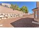 Enclosed backyard featuring rock landscaping, brick perimeter walls, and mature trees at 7621 Breed Hill St, Las Vegas, NV 89149