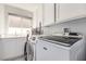 Well-lit laundry room with white cabinetry, sink, and modern washer and dryer at 9440 Grenville Ave, Las Vegas, NV 89134
