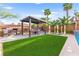 Outdoor living space showcasing a pergola-covered dining area, grill, and refreshing pool with verdant turf at 9685 Stonily Ln, Las Vegas, NV 89178