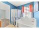 Blue bathroom featuring a bathtub/shower combination with white tile and a decorative curtain, and a large window at 9685 Stonily Ln, Las Vegas, NV 89178