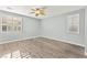 A well-lit bedroom featuring hardwood floors, neutral walls, a ceiling fan, and two large windows with shutters at 9685 Stonily Ln, Las Vegas, NV 89178