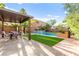 Inviting backyard oasis featuring a shimmering pool, a covered patio, and lush, green landscaping at 9685 Stonily Ln, Las Vegas, NV 89178