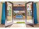 Inviting view of a private pool and outdoor space through open French doors with curtains at 9685 Stonily Ln, Las Vegas, NV 89178