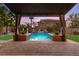 Stunning pool view framed by a covered patio and swaying palm trees, perfect for relaxing and entertaining at 9685 Stonily Ln, Las Vegas, NV 89178
