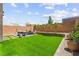 Expansive backyard with lush green lawn, complemented by a stylish patio set and neatly arranged potted plants at 9743 Mojave Mountain St, Las Vegas, NV 89166