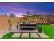 Beautifully landscaped backyard with ambient lighting, lush green grass, and a comfortable outdoor seating area at 9743 Mojave Mountain St, Las Vegas, NV 89166