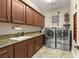 A home's laundry room featuring modern washer and dryer units, ample storage, and stylish granite counters at 9747 Cathedral Pines Ave, Las Vegas, NV 89149
