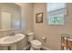 Downstairs powder room with pedestal sink, toilet, and large window at 9785 W Meranto Ave, Las Vegas, NV 89178
