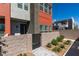 Modern townhouse with red and gray facade, gated entry, and manicured landscaping on a sunny day at 9844 Kings Glen St, Las Vegas, NV 89141