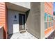 Close-up of a modern townhome entrance featuring a gray facade, red accents, and a welcoming doormat at 9844 Kings Glen St, Las Vegas, NV 89141