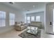 Bright living room features light colored sofas, a glass coffee table, herringbone floors, and large windows at 9844 Kings Glen St, Las Vegas, NV 89141