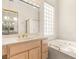 Bathroom vanity with dual sinks and a jacuzzi tub under a glass block window at 10548 Findlay Ave, Las Vegas, NV 89134