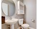 Classic-style half bathroom features a pedestal sink, round mirror, and built-in storage at 262 Calvino Ave, Las Vegas, NV 89183