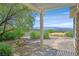 Landscaped backyard with a covered patio, rock accents, mature trees, mountain views and a stone fire pit at 2899 Brook Trout Ct, Henderson, NV 89052
