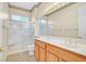 Well-lit bathroom featuring double sinks, vanity, walk-in shower and a decorative light fixture above the mirror at 2899 Brook Trout Ct, Henderson, NV 89052