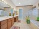 Main bathroom featuring double sinks, tub, shower, and patterned wallpaper at 2899 Brook Trout Ct, Henderson, NV 89052