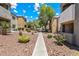 Well-maintained exterior of condominium buildings with mature trees, shrubs, and a stone pathway at 3151 Soaring Gulls Dr # 1066, Las Vegas, NV 89128