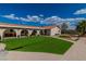 Exterior view of the home with manicured artificial turf, a tile roof, and a covered patio with arched supports at 465 E Robindale Rd, Las Vegas, NV 89123