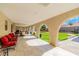 Covered patio with arched supports, tile flooring, and comfortable seating overlooking the manicured backyard at 465 E Robindale Rd, Las Vegas, NV 89123