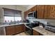 Modern kitchen featuring stainless steel appliances, granite countertops, and wooden cabinets with dark hardware accents at 4732 S Adriano Way, Pahrump, NV 89061