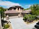Tan two-story home featuring a two-car garage, stone accents, and tile roof, set against a blue sky backdrop at 5568 Table Top Ln, Las Vegas, NV 89135