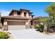 A charming tan home with a two-car garage, stone pillars, desert landscaping, and a bright blue sky at 5568 Table Top Ln, Las Vegas, NV 89135