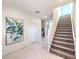 Bright entryway with staircase, neutral tile flooring, modern art, and access to a bathroom at 1289 Miller Springs Ln # 96, North Las Vegas, NV 89084