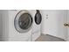 A modern laundry room with a white, front-load washer and dryer set and tile flooring at 1613 Glenrosa Dr, North Las Vegas, NV 89031
