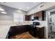 Well-equipped kitchen with dark cabinets, white countertop, stainless steel appliances and convenient access to the laundry room at 209 Camino Vista St, Henderson, NV 89012