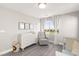 Bright Bedroom with a dresser changing table, gray rocker, and view to the outdoors at 3058 Casarano Ct, Henderson, NV 89044