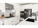 Close-up of a modern kitchen showcasing white cabinets, quartz counters, and stainless-steel appliances at 3058 Casarano Ct, Henderson, NV 89044