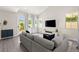 Comfortable living room with a plush gray sectional sofa, large windows, and a view of the backyard at 3058 Casarano Ct, Henderson, NV 89044