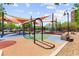 Outdoor playground with swings, slides, climbing structures and colorful, soft ground surfaces at 3058 Casarano Ct, Henderson, NV 89044