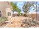 The backyard features a low brick wall, mature trees, and bare soil at 4516 Cielo Ln, Las Vegas, NV 89130