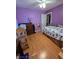 Bright purple bedroom includes a dollhouse and wood laminate flooring, creating an inviting atmosphere at 6363 Berry Patch Way, Las Vegas, NV 89142
