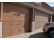 Close-up of brown, paneled garage doors with white trim and a partial view of a white vehicle at 6363 Berry Patch Way, Las Vegas, NV 89142
