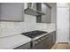 Close-up of the kitchen cooktop, subway tile backsplash, and gray cabinets in a modern design at 6433 Farness St, Las Vegas, NV 89135