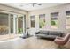 Bright living room with large sliding glass door, three large windows, wood floors, sofa, treadmill and accent chair at 6433 Farness St, Las Vegas, NV 89135