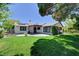 A lovely backyard has green grass, trees, patio, and the back of the home with solar panels at 7100 Carrondale Way, Las Vegas, NV 89128