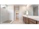 Bright bathroom featuring double vanity, walk-in shower, neutral tiling, and access to a walk-in closet at 769 Cloud Creek St, Henderson, NV 89011